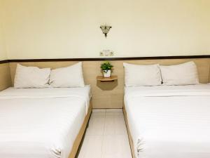 日惹Musafira Hotel Syariah Malioboro Yogyakarta Mitra RedDoorz的两张睡床彼此相邻,位于一个房间里