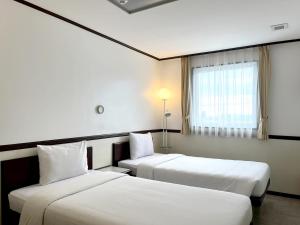 宿务Toyoko Inn Cebu的酒店客房设有两张床和窗户。