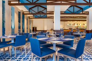 卡拉德米哈斯洛斯阿米戈斯海滩俱乐部钻石度假酒店的一间设有蓝色桌椅的餐厅和一间酒吧