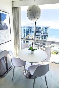 圣地亚哥Luxury Beach-Front High-Rise Apartment的配有大窗户的客房内的白色桌椅