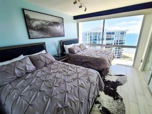 圣地亚哥Luxury Beach-Front High-Rise Apartment的一间卧室设有两张床和大窗户