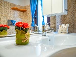 奇亚Appartamenti La Conchiglia的浴室水槽,上面有红玫瑰花,花瓶上