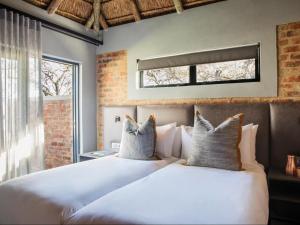 Dinokeng Game ReserveNAKO Safari Lodge的一间卧室设有两张白色的床和窗户