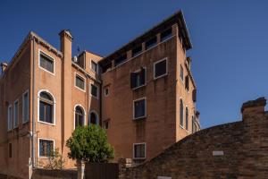 威尼斯Santa Croce Design Apartment R&R的一座古老的砖砌建筑,前面有一棵树