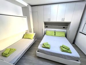 瓦拉泽Green House Varazze的小客房内的两张床,配有绿色枕头