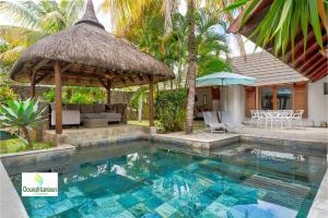 格兰贝伊Oasis 1 Villa Tropicale的一个带遮阳伞和房子的游泳池