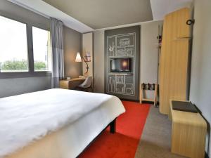 圣艾蒂安Ibis Saint Étienne - La Terrasse的酒店客房设有一张大床和一台电视机。