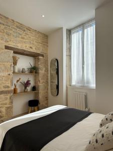 第戎La Cabotte - Confort & Charme au Centre Historique - Balcon sur cour的一间卧室设有一张大床和石墙