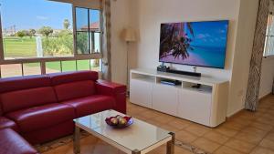 卡勒达德福斯特Villa BONITA on Golf in El Descanso ,Caleta Fuste-Fuerteventura的客厅配有红色沙发和平面电视