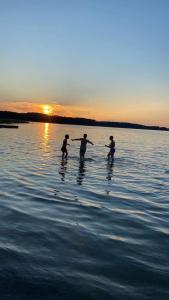 吉日茨科Sterla - Masuria的日落时分,有三人站在水面上