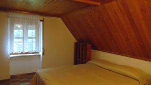 LannaLA CASA DEI RICORDI的一间卧室设有一张带木制天花板和窗户的床。