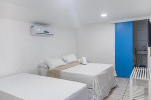 嘎林海斯港Pousada La Bella Luna的白色的客房设有两张床和蓝色的墙壁
