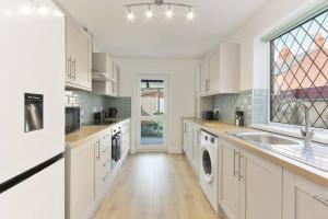 Great CoatesModern home near Alexandra Dock的厨房配有白色橱柜、水槽和窗户。