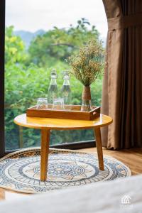 木州县Avatar Homestay & Coffee - Mộc Châu的一张桌子,上面有玻璃杯,还有一盘鲜花