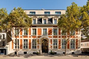 布洛涅-比扬古Le Parchamp, a Tribute Portfolio Hotel, Paris Boulogne的一座公寓楼,有门和树木