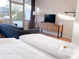 诺伊斯Central Apartment Rhein Neuss-Düsseldorf Messe的一间卧室配有一张床、一台电视和一张沙发