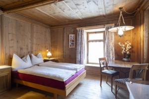 阿尔代兹Chasa Broel Ferienhaus mitten in Ardez的一间卧室配有一张床、一张书桌和一个窗户。