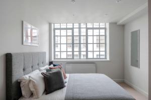 伦敦London's Calling - Farringdon - by Frankie Says的卧室配有带枕头的床铺和窗户。