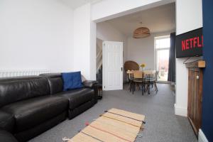 卡迪夫Central Cardiff - 3 Bedroom Home - Free Parking - Walk to Shopping Town Centre And Cardiff Castle的客厅配有黑色真皮沙发和桌子