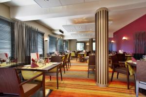 吕克瑟伊莱班Mercure Hexagone Luxeuil的餐厅设有木桌、椅子和紫色墙壁