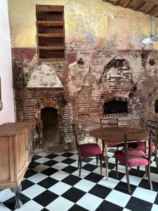 圣安东尼奥德阿雷科Hostel El Puesto的配有桌椅和砖墙的房间