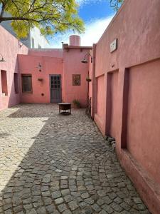 圣安东尼奥德阿雷科Hostel El Puesto的粉红色的建筑,前面有长凳