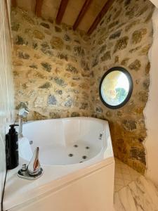 塞吉阿诺Podere Montale Il Borgo的带浴缸的浴室和石墙