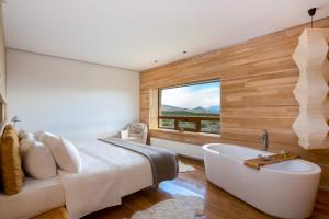 百内三塔Tierra Patagonia的卧室配有床、浴缸和窗户。