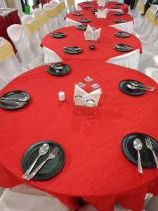 博帕尔HOTEL R K PALACE的一张长红色的桌子,上面有黑板和银器