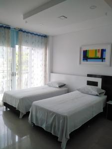 AguazulHotel Aguazul Plaza Centro的白色客房的两张床,设有窗户