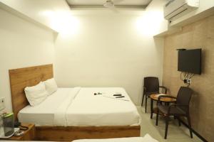 孟买Hotel Shiv Leela Grand的酒店客房带一张床、一张桌子和椅子