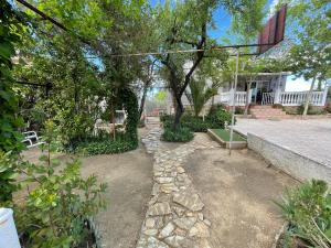 纳瓦尔卡内罗Villa Flores的一座花园,花园内有树木和石头小径