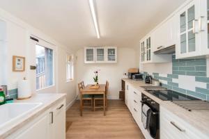北贝里克Stunning Stables Cottage in East Lothian Country Estate的厨房配有白色橱柜和木桌