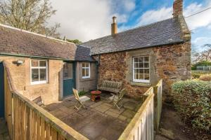 北贝里克Stunning Stables Cottage in East Lothian Country Estate的石头小屋设有木栅栏和庭院。