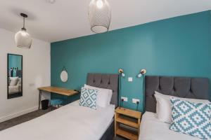 德比Deluxe Studio Apartments的一间卧室设有两张床和蓝色的墙壁