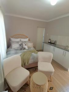 东伦敦Izibusiso Guest room的一间卧室配有一张床和两把白色椅子
