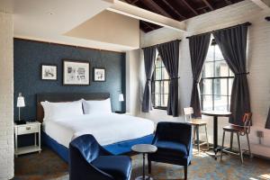 HastingsThe Confluence Hotel的酒店客房带一张床、椅子和窗户
