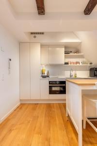 哥本哈根Charming Loft City Center的厨房铺有木地板,配有白色橱柜。