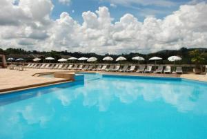 塞拉内格拉Apartamento flat em Serra Negra (A)的度假村的游泳池配有椅子和遮阳伞