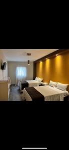 La BarcaHotel Real Briseñas的酒店客房设有两张床和黄色的墙壁