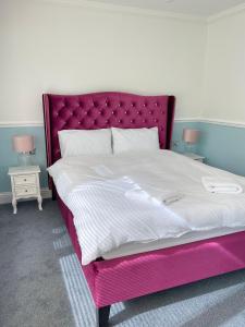 诺里奇Arrandale Lodge的一张带粉红色床架和两张桌子的床