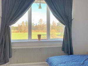 韦特兰达Holiday home VETLANDA的一间卧室设有窗户,配有蓝色窗帘和一张床