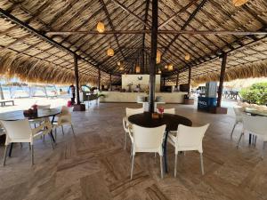 San Pedro de Coche撒索勒蓬布兰卡酒店的一个带桌椅的用餐区和稻草屋顶。