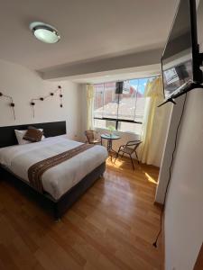 库斯科Cusco Rooms的一间卧室配有一张床、一张桌子和一台电视