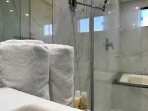 帕劳阿佩巴斯Atrium Confort Hotels的带淋浴的浴室和浴缸上的白色毛巾