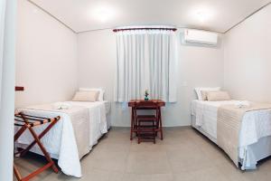 巴拉格兰德Pousada Estrela do Mar的客房设有两张床、一张桌子和一扇窗户。