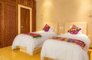 图卢姆Niwa Tulum的一间卧室配有两张床、白色床单和色彩缤纷的枕头