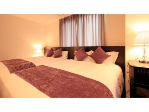 福井Centurion Hotel Villa Suite Fukui Ekimae - Vacation STAY 34640v的卧室配有一张带紫色枕头的大型白色床。