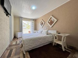 坎波斯杜若尔当Hotel Solar da Montanha的一间卧室配有一张床、一张桌子和一个窗户。