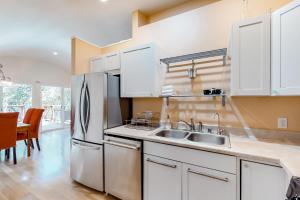 佩塔卢马Treescape的厨房配有白色橱柜和不锈钢冰箱